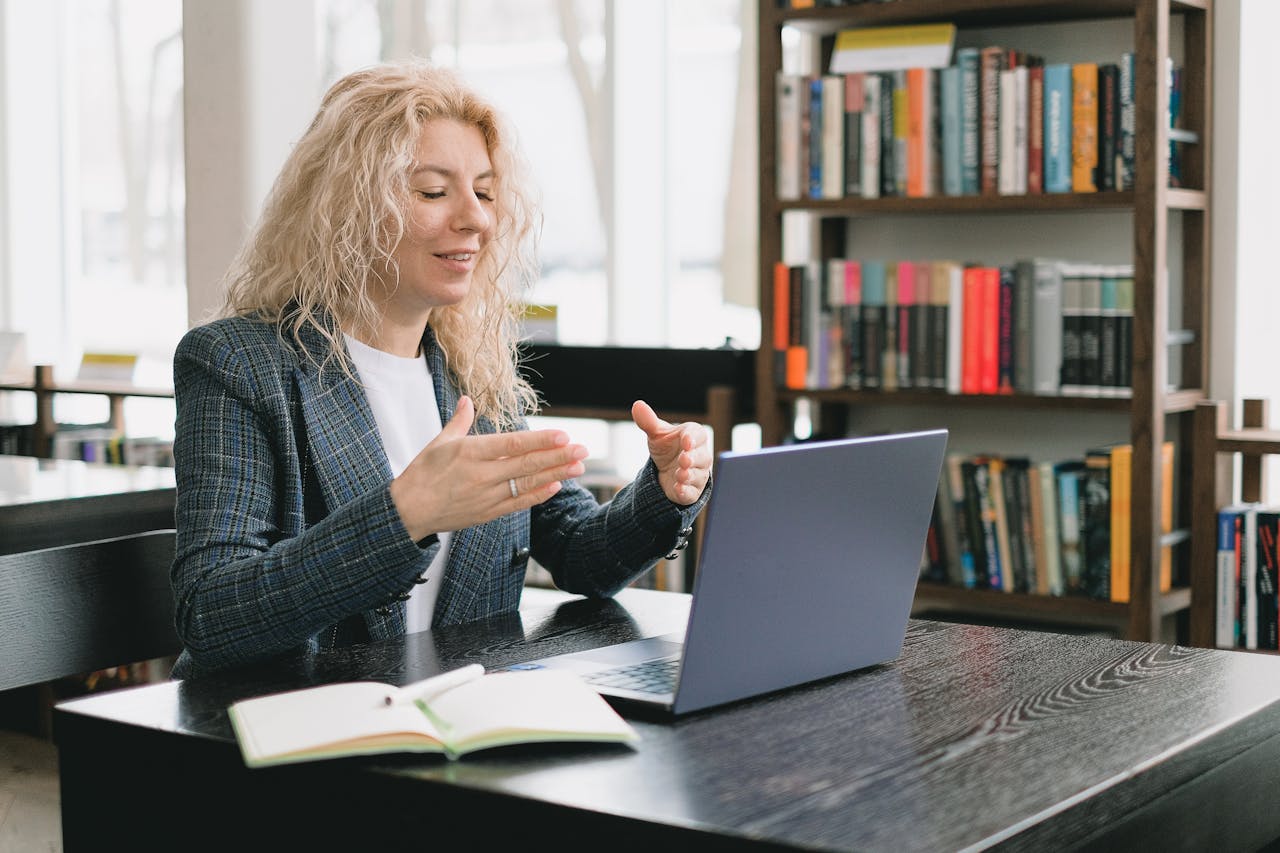 Smiling woman having video chat via laptop in library.