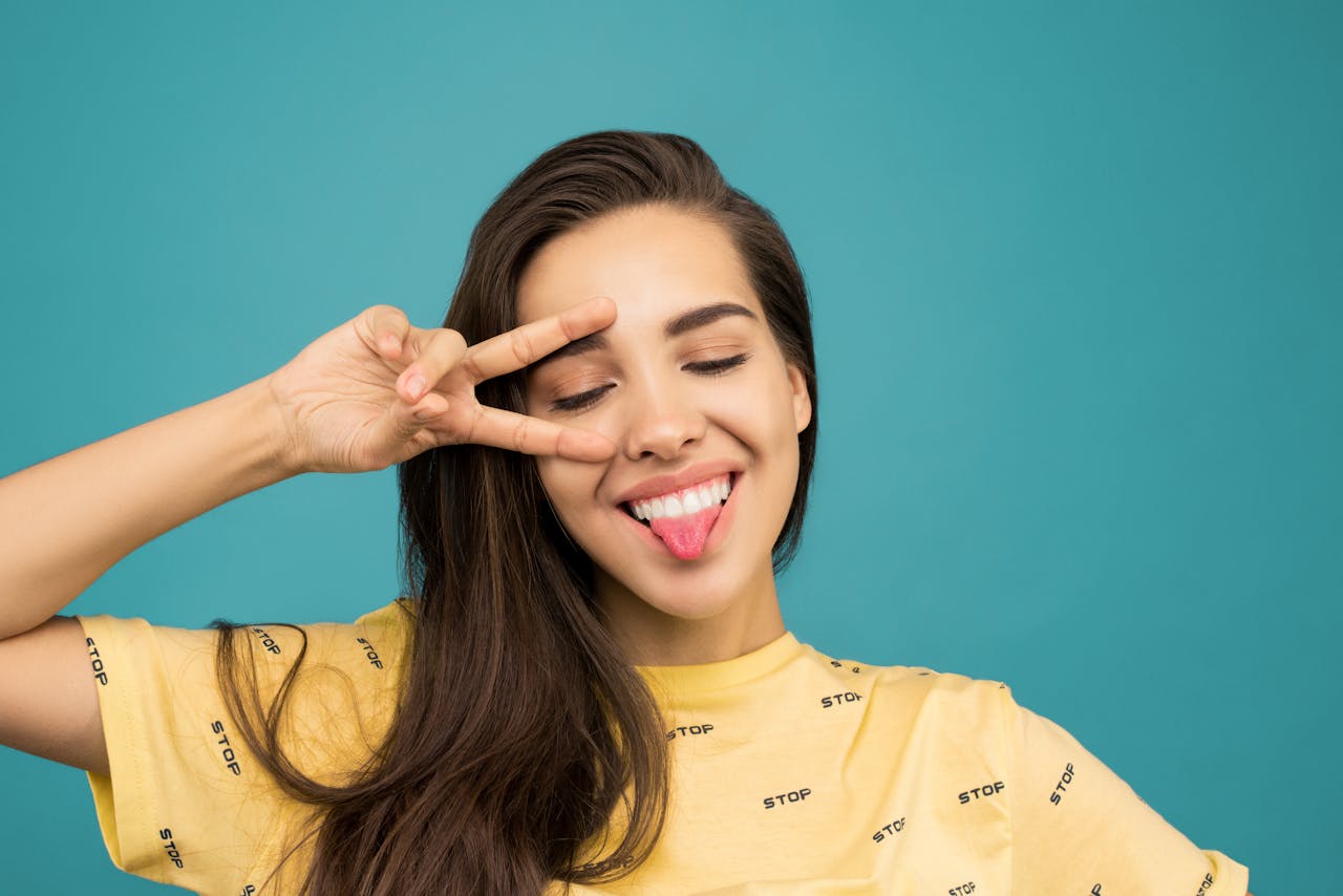 A Woman Wearing Yellow Shirt and smiling while stacking her tongue