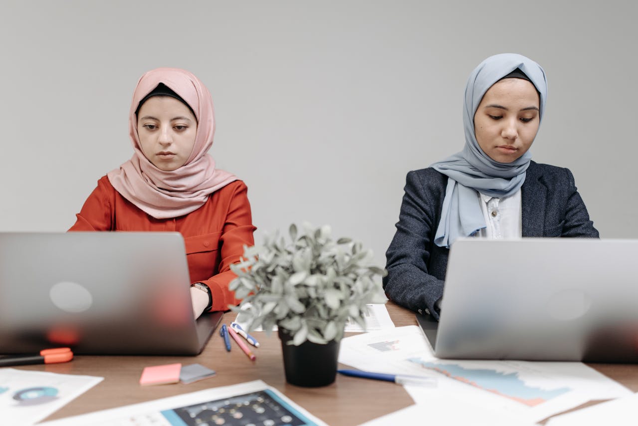 Women Using Laptops at a Wooden Table