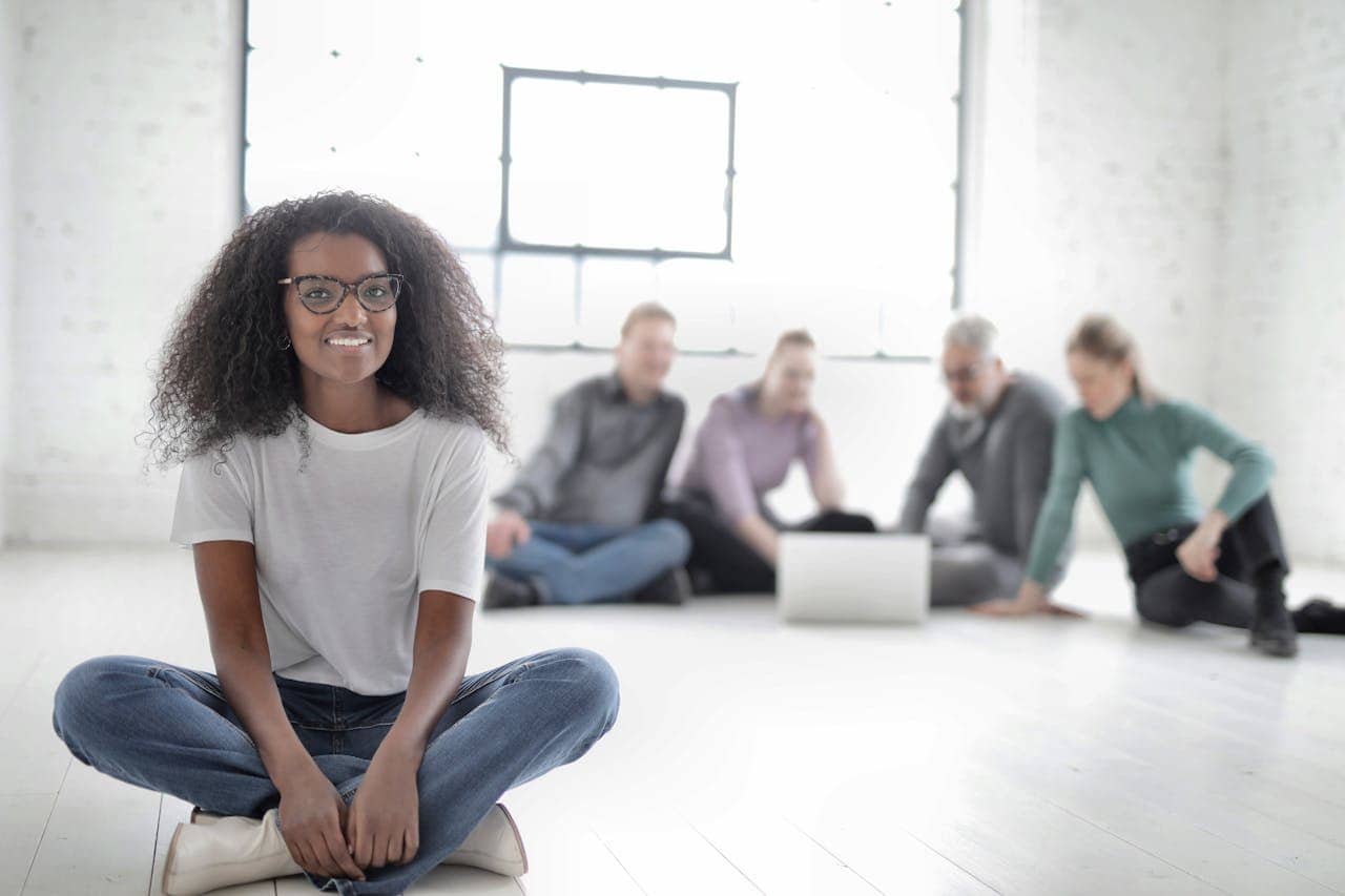 Group Of People Sitting On The Floor With Focus On Woman in White Crew Neck T-shirt