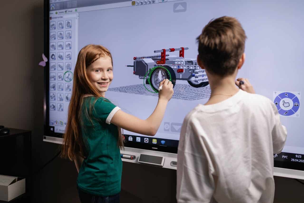 Two Kids Standing by an Interactive Board.