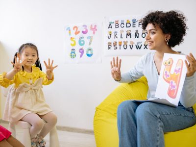 Girl in Yellow Long Sleeve Dress Learning To Count With Her Teacherز