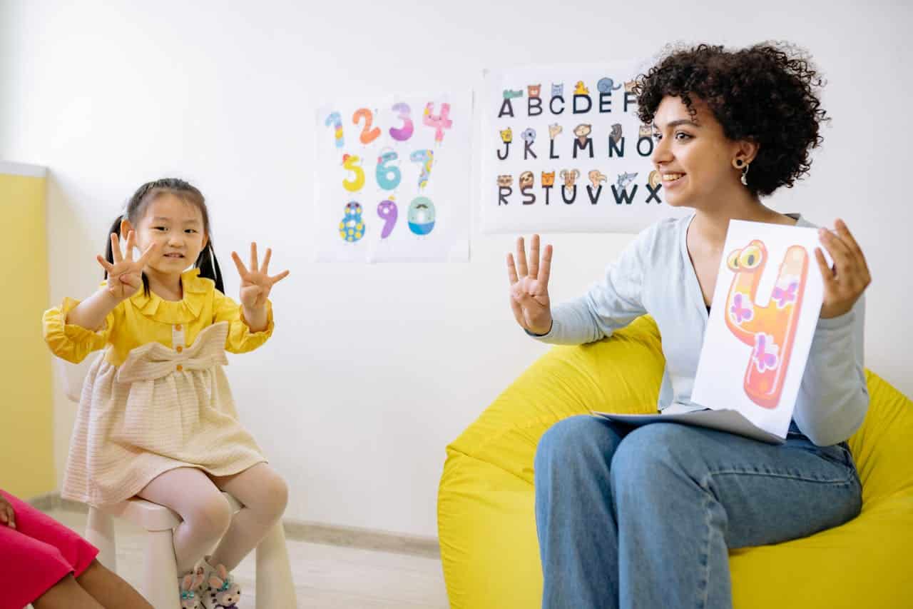 Girl in Yellow Long Sleeve Dress Learning To Count With Her Teacherز